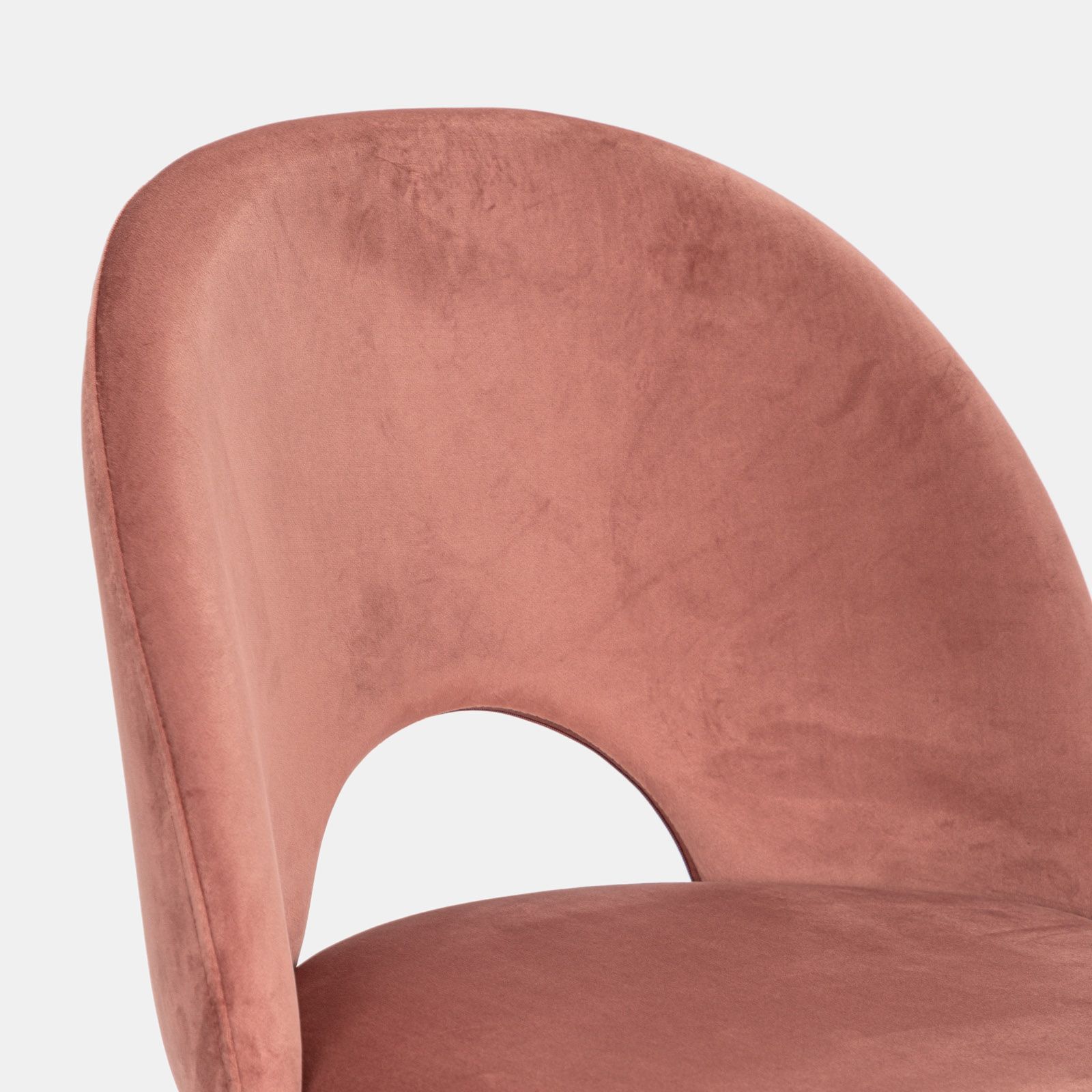 Una sedia rosa con rivestimento in velluto rosa si trova in una stanza con  un muro rosa dietro.